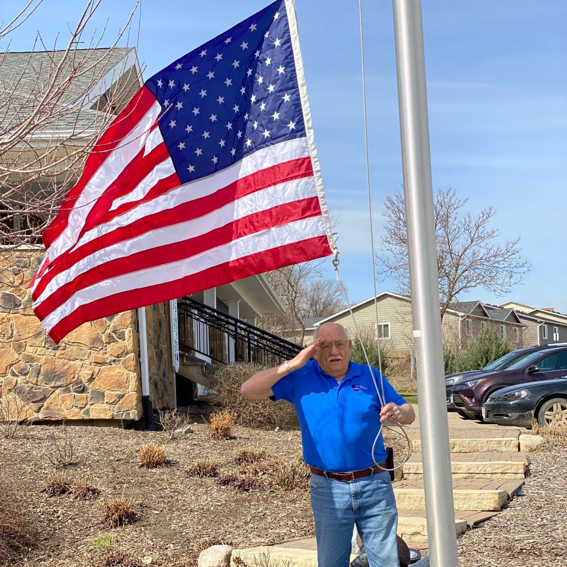 Man saluting next to flag at Iowa River Hospice.